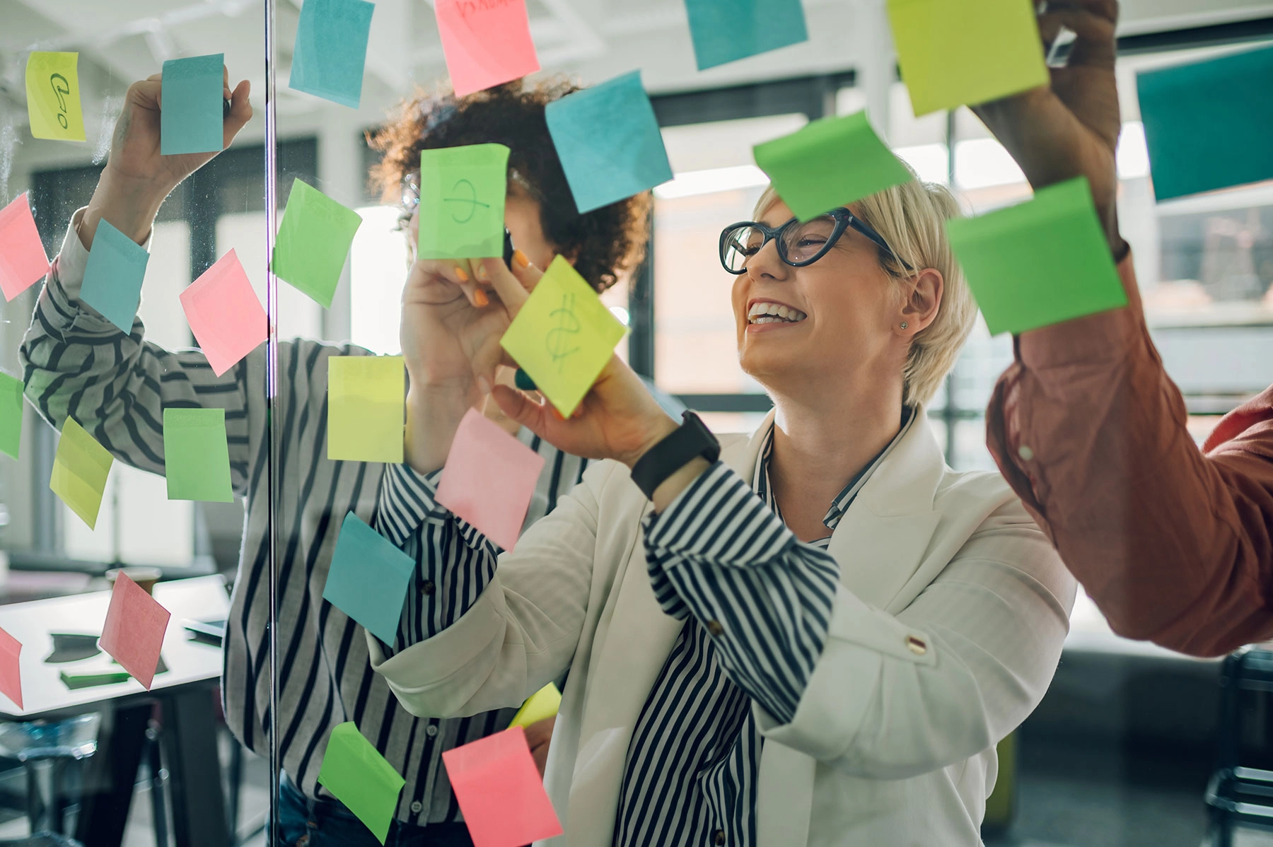 Profesionales organizando ideas y tareas en una pared de notas.