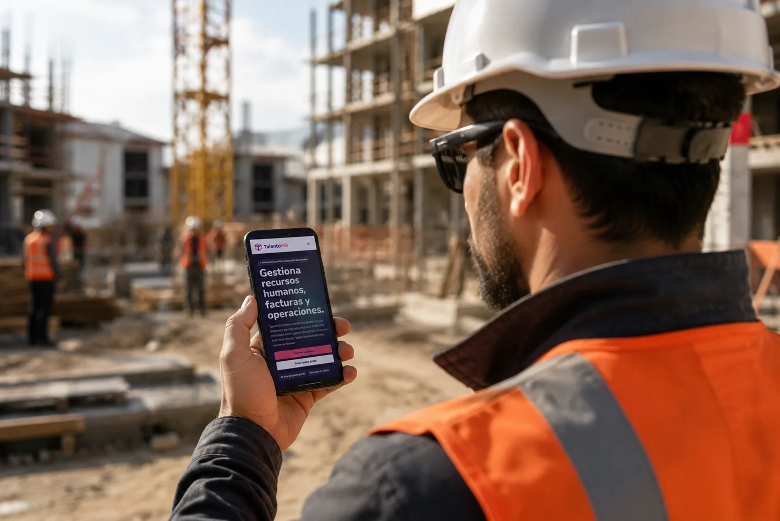 Trabajador de construcción consultando TalentoHQ desde el móvil en una obra